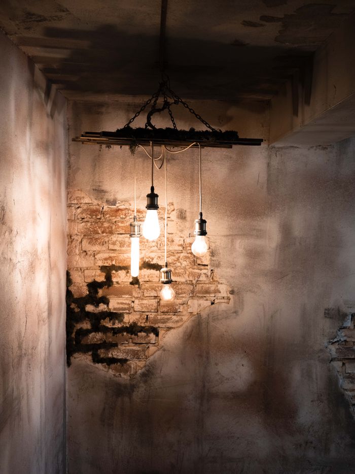 Dimly lit room with exposed brick walls and hanging light bulbs creating a moody ambiance.