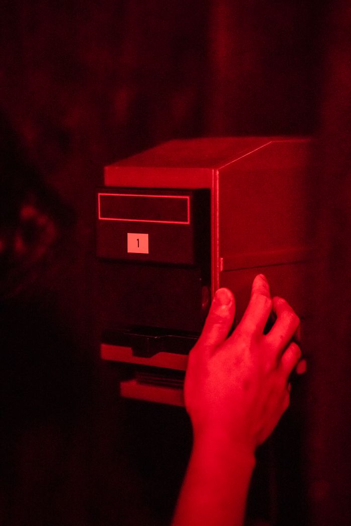A hand operates a device in a red-lit darkroom, showcasing photography technology.